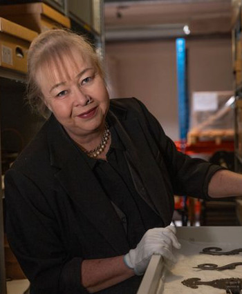 Anna Gullmark, iförd handskar i ett museiarkiv
