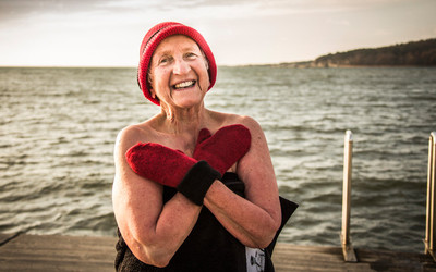 Äldre leende kvinna står på bryggan efter ett vinterbad