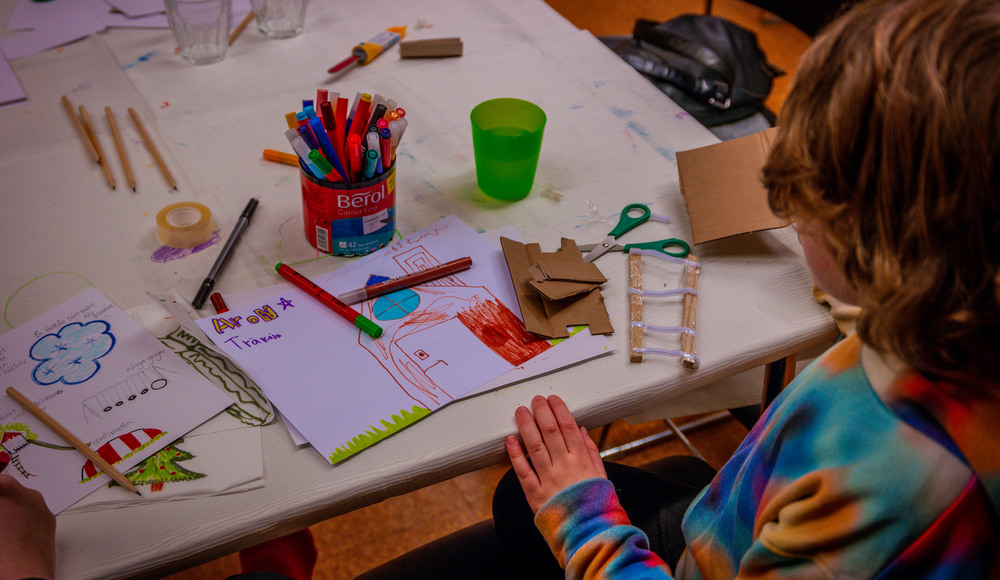 Ett barn ritar på papper och klipper i kartong för att gestalta sin idé