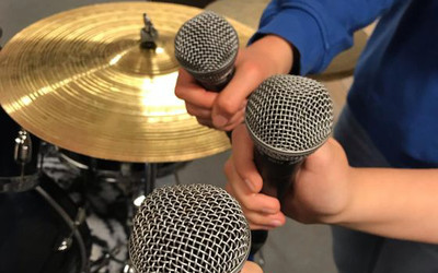 Tre händer håller i varsin mikrofon i musikstudion på Ungdomens Hus